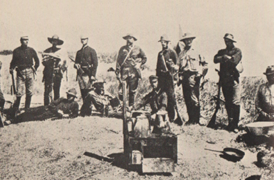 Grinnell standing second from left in wide brimmed hat, holding an antelope and Springfield Trapdoor rifle.